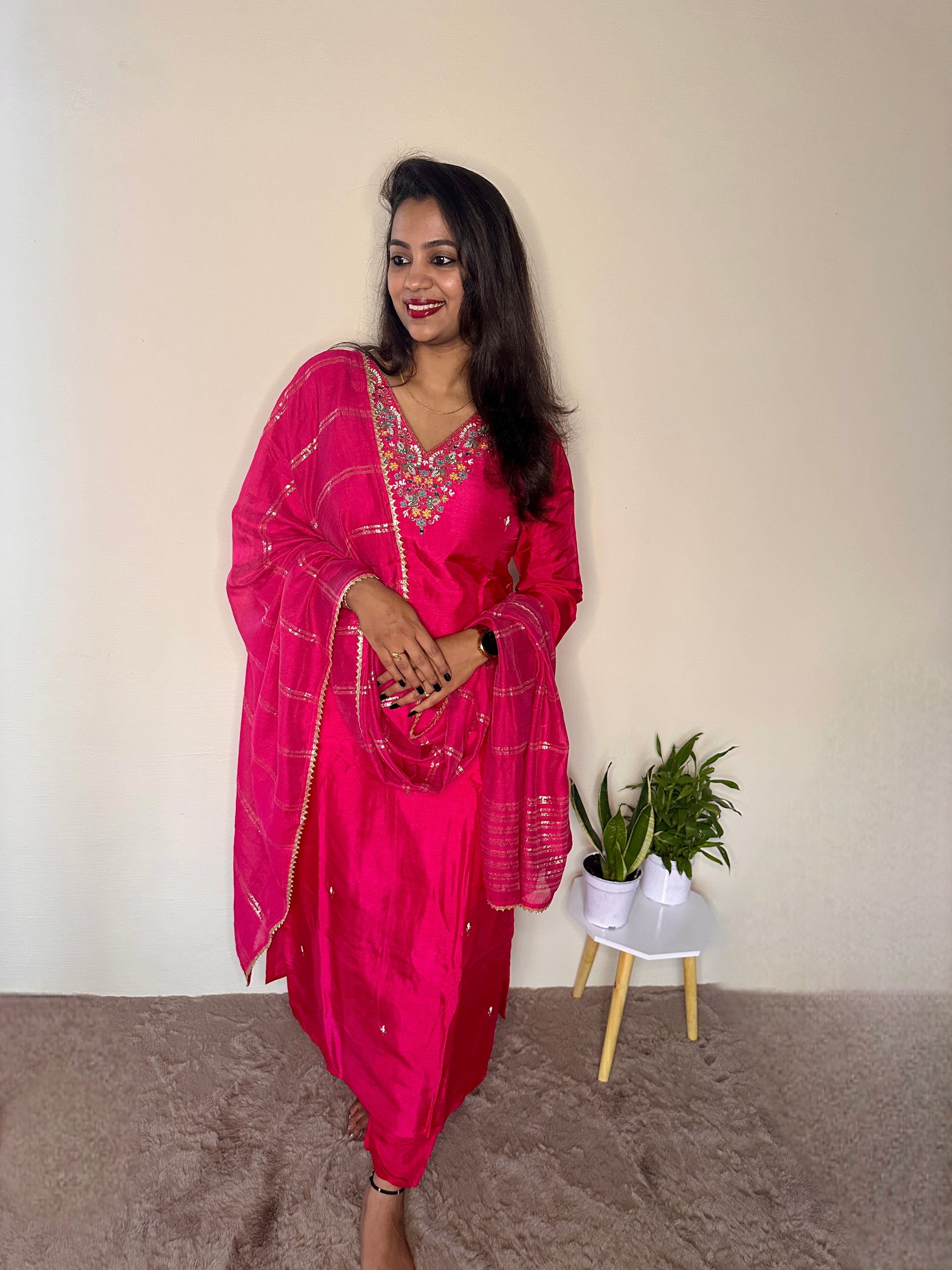 Woman wearing a pink dola silk salwar suit with hand embroidered neckline and matching dupatta