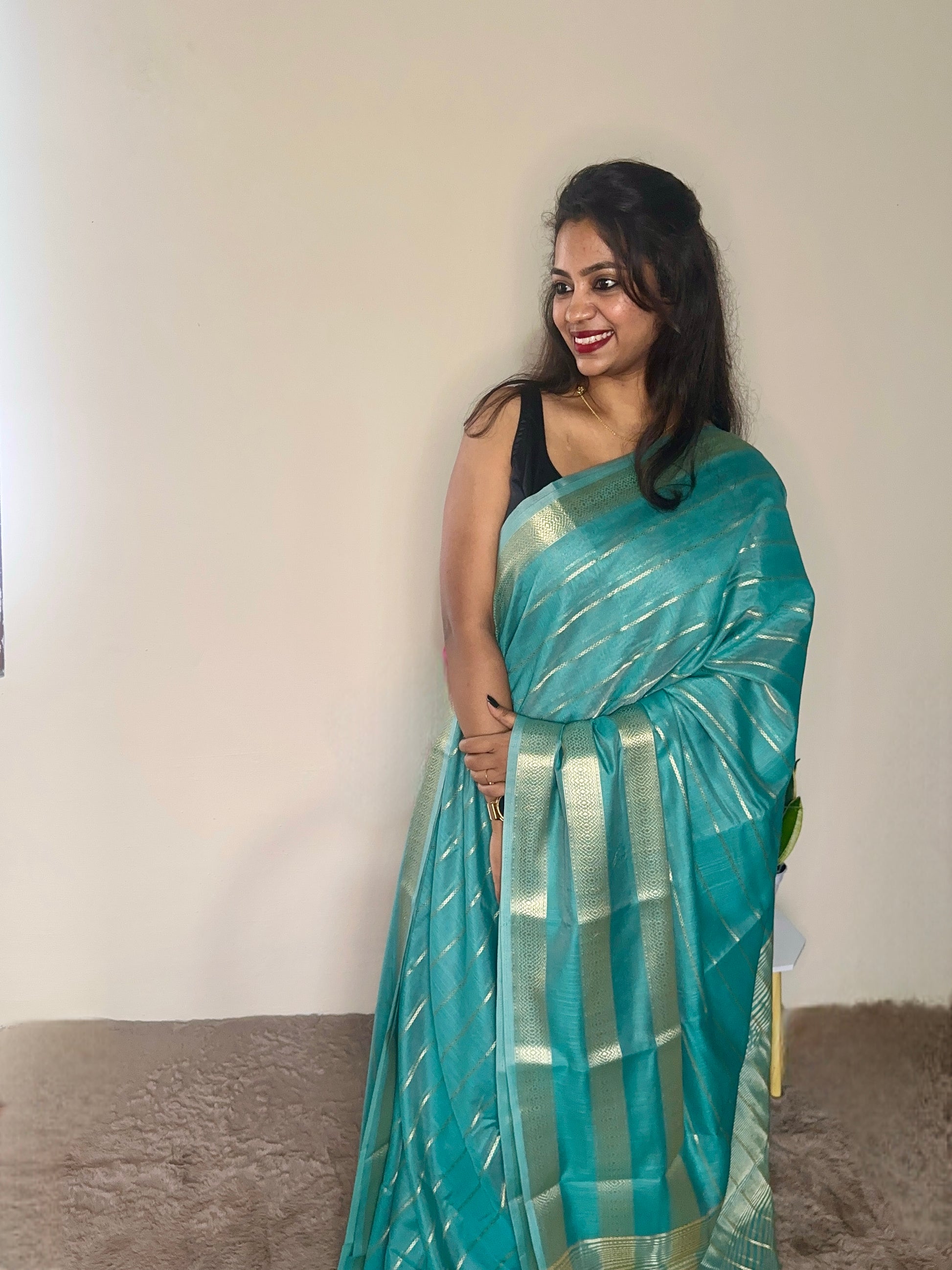 Model wearing a turquoise blue soft cotton saree with gold zari detailing, styled for festive wear – Jayithva