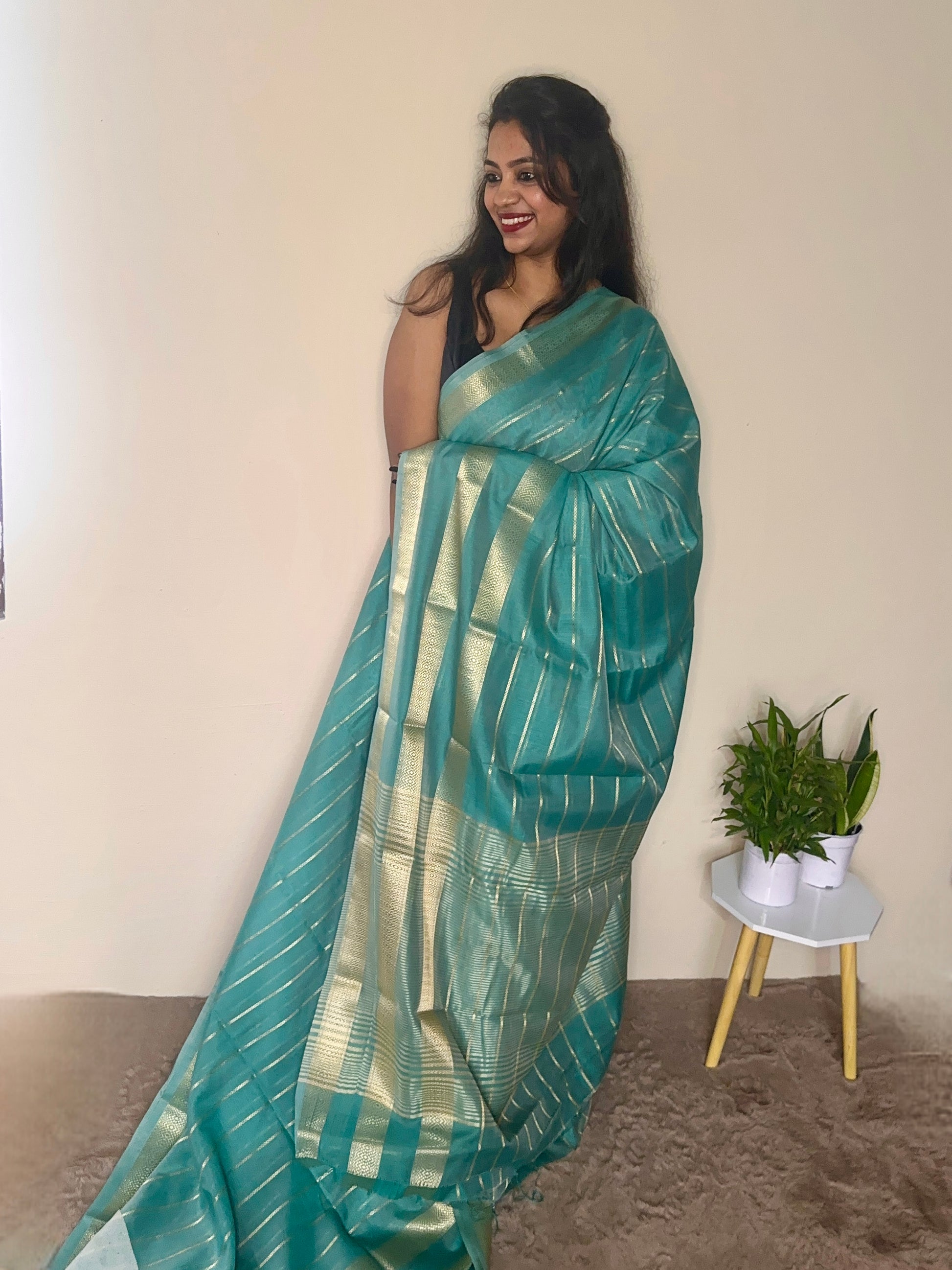 Model wearing a turquoise blue soft cotton saree with gold zari detailing, styled for festive wear – Jayithva