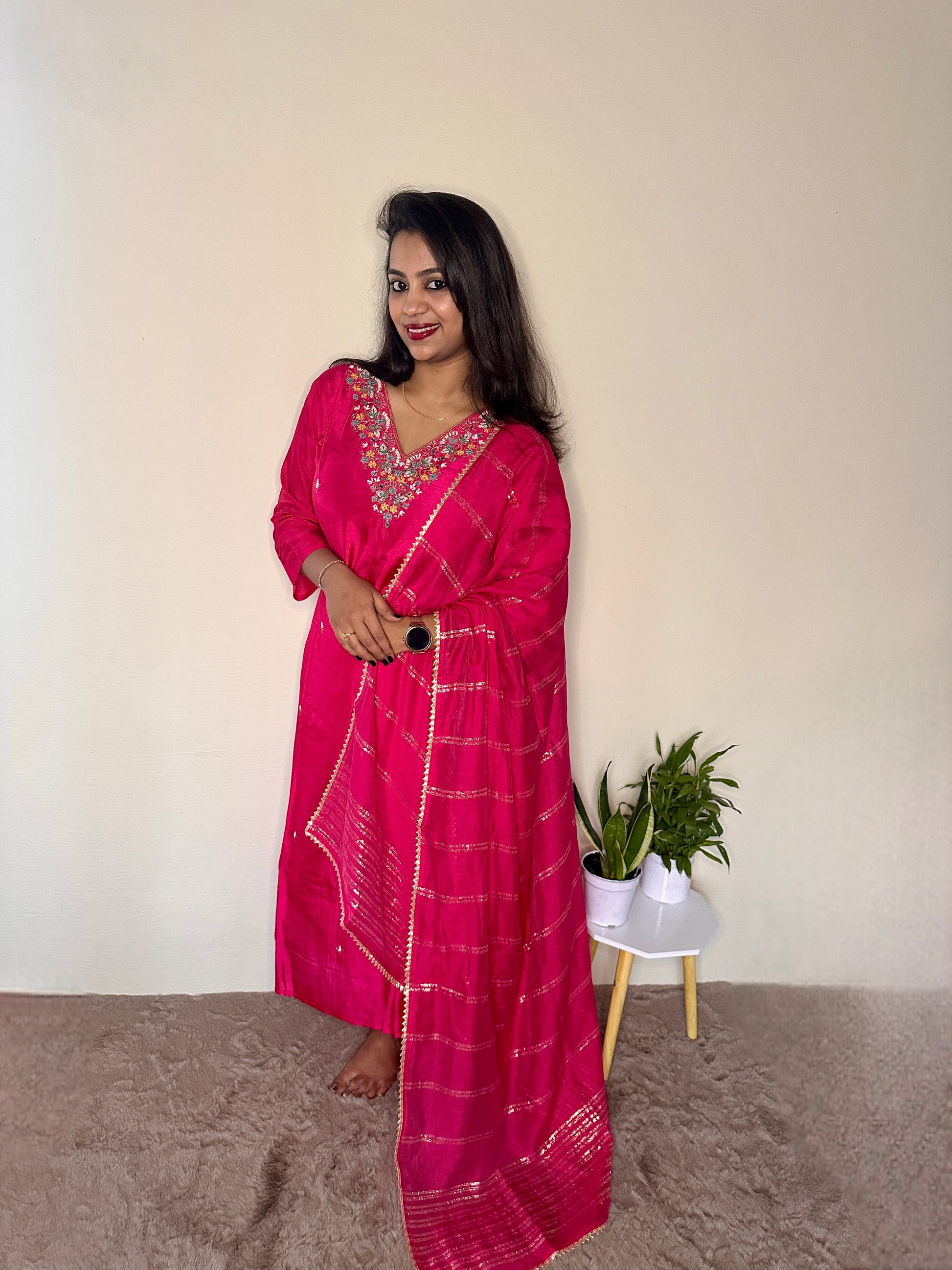 Woman wearing a pink dola silk salwar suit with hand embroidered neckline and matching dupatta